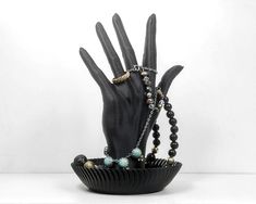 a hand is holding some beads in a black bowl with it's fingers out