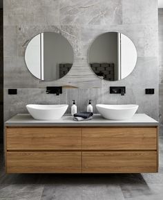 two white bowls on top of a wooden vanity