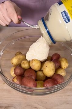 a person pouring mayonnaise on potatoes in a bowl