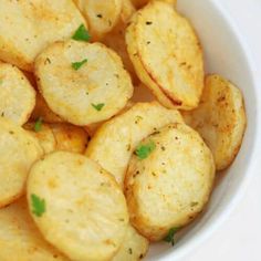 a white bowl filled with cooked potatoes and garnished with parsley on top