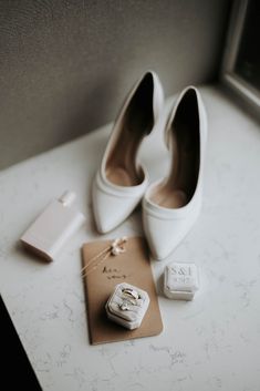 a pair of white high heels sitting on top of a table next to a card