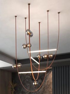 a modern chandelier hanging from the ceiling in a living room with stone wall