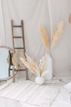 a white room with a chair, mirror and vase on the floor next to it