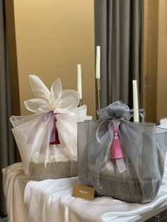 two baskets with bows and tags on them sitting on a table in front of candles