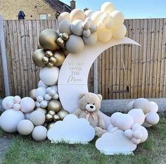 a teddy bear sitting in front of a balloon arch