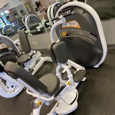 there are many exercise machines in this gym room with no one on the bike seat