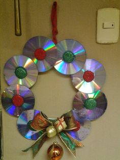 a christmas wreath made out of cd's hanging on a wall with bells and ornaments