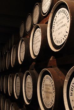 several rows of wine barrels stacked on top of each other in a room with dark walls