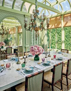 a dining room table set with place settings and flowers in vases on the tables