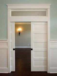 an open door leading into a room with hard wood flooring and white painted walls