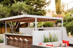 an outdoor kitchen with seating and lights