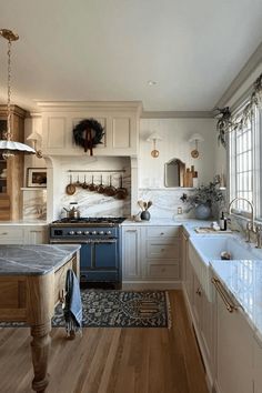 a large kitchen with white cabinets and blue stove top oven next to a wooden floor