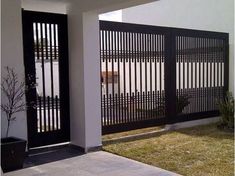 a black and white gate is in front of a house with a potted plant