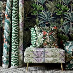 a chair and two large pillows in front of a wallpapered room with palm trees