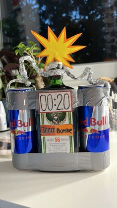 two beer cans sitting on top of a table with a yellow star above them and another can in the background