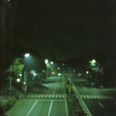 an empty street at night with lights shining on the road and trees in the background