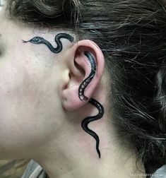 a woman with a black snake tattoo on her ear