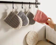 a person is holding two tea towels in front of three hanging stocking holders on a wall