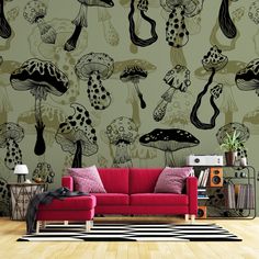 a red couch sitting in front of a wall with black and white mushrooms on it