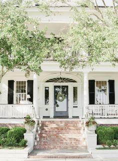 a white house with black shutters on the front porch and steps leading up to it