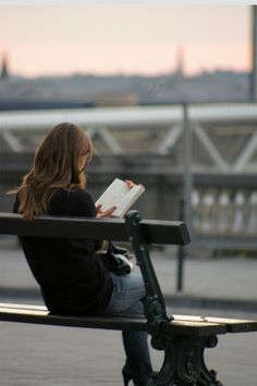 a woman sitting on a bench reading a book