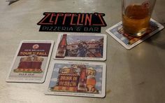 four coasters sitting on top of a table next to a beer glass and bottle