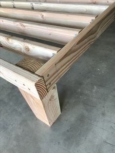 a close up of a wooden bench made out of wood planks on the ground