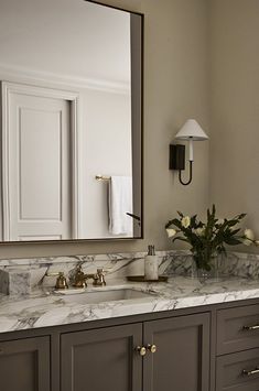 a bathroom with marble counter tops and gray cabinets