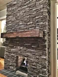 a stone fireplace in a living room with wood flooring