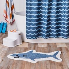 a blue and white bathroom with a shark rug on the floor next to a shower curtain