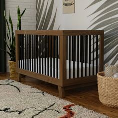 a baby crib in the corner of a room next to a potted plant