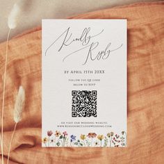 the wedding card is on top of an orange cloth with flowers and grass in it