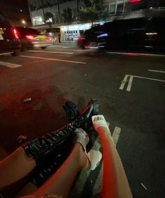 a person is riding their bike down the street at night with cars passing by in the background