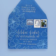 a blue envelope with white flowers and stamps on the front, featuring an image of a woman's face