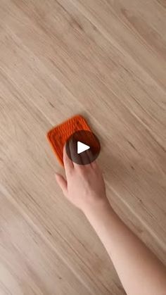 a person holding an orange object on top of a wooden floor