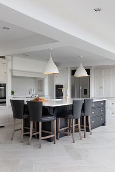 a large kitchen with an island and bar stools in the center, surrounded by white cabinets