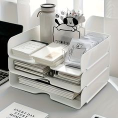 a stack of papers sitting on top of a desk next to a laptop