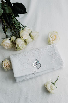 two wedding rings are laying on a white cloth with flowers and greenery around them