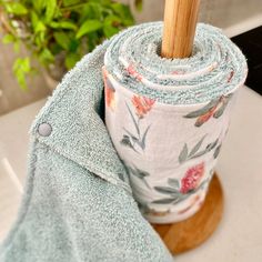 a rolled up towel sitting on top of a wooden stand next to a potted plant