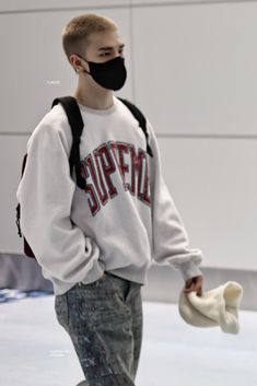 a young man wearing a face mask and holding a skateboard in front of him