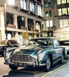 an old car is parked on the side of the road in front of some buildings