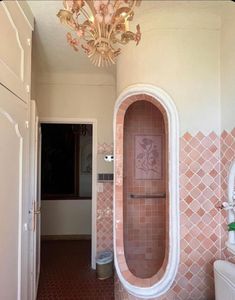 a bath room with a toilet and a chandelier hanging from it's ceiling