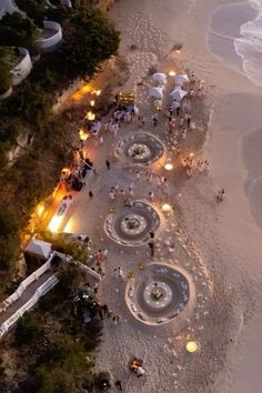 an aerial view of the beach at night with lit up tables and umbrellas on it