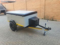 an enclosed trailer is parked in front of a brick wall and has wheels on the side