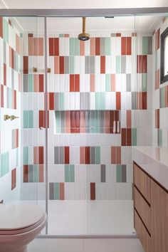 a bathroom with a toilet, sink and shower stall covered in multicolored tiles