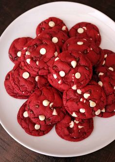 a white plate topped with red cookies covered in white chocolate chips