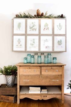 an old dresser with jars and pine cones on top, surrounded by other christmas decorations