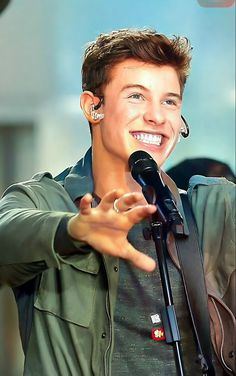 a young man holding a microphone in front of a microphone with his hand out to the side