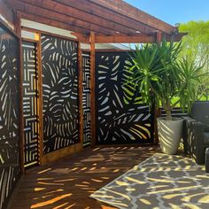 an outdoor living area with black and white patterned screens on the wall, potted plant in front