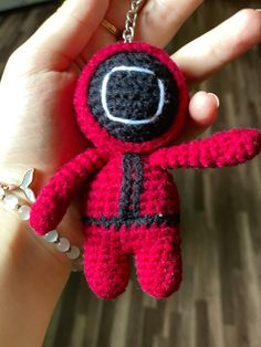 a hand holding a small crocheted keychain in the shape of an astronaut